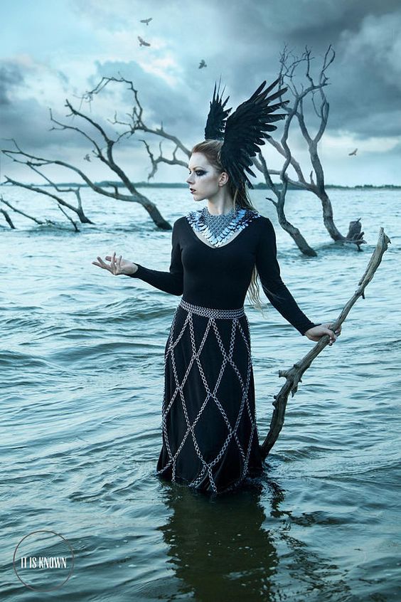 Woman in scalemaille collar and chainmaille skirt and winged headgear standing in water