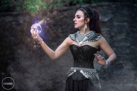 woman with scalemaille collar and bustle holding glowing orb