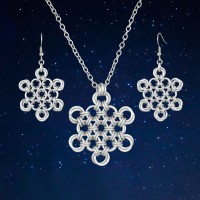white chainmaille pendant and earring set - each in a snowflake pattern against a starry-night background