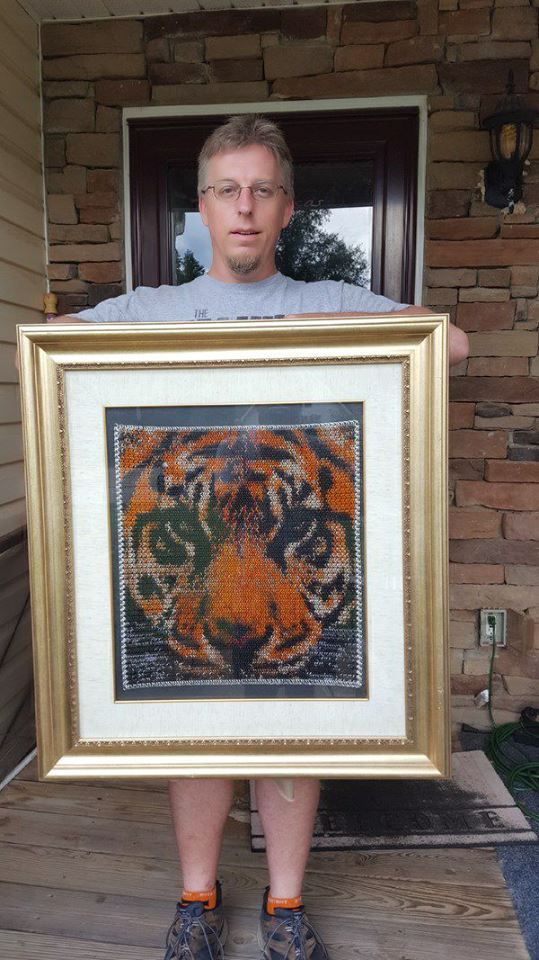 artist tony moeller holding framed chainmaille tiger inlay