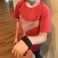 young boy holding up wrist with black chainmaille cuff